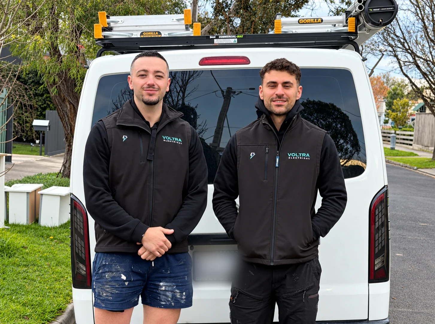 Two Voltra electricians standing in front of their white work van