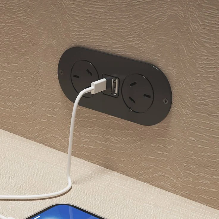 Black double power point with a USB charging port, charging a phone